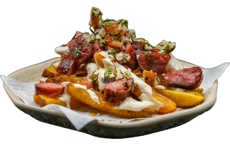 Salchipapa: batata frita com rodelas de chouriço crioulo, molho de queijo creme, chimichurri e pico de gallo.